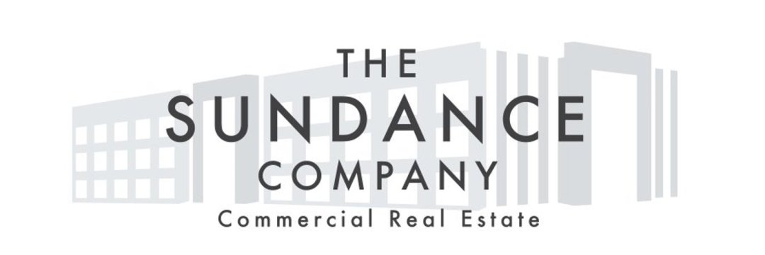 The Sundance Company logo with black text reading ‘The Sundance Company – Commercial Real Estate’ on a white background with a faint building graphic.